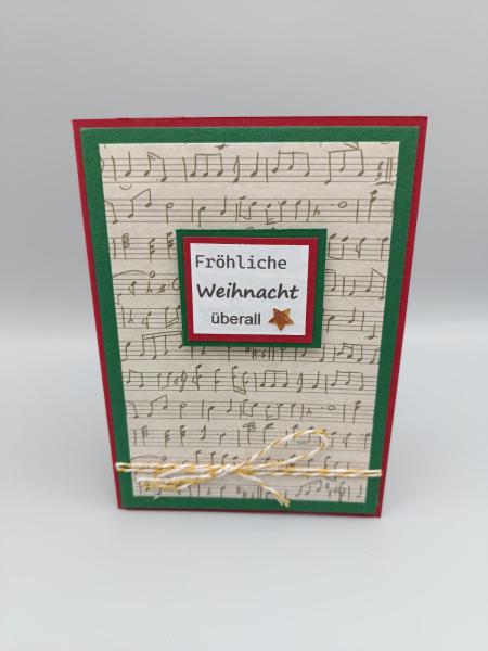 Handgemachte Weihnachtskarte mit Notenhintergrund und Stern – „Fröhliche Weihnacht überall“